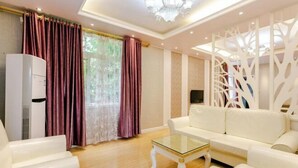 A living room with a white sofa, a glass coffee table, and a white radiator. - Gongbaofu Hotel (Chongzhou)