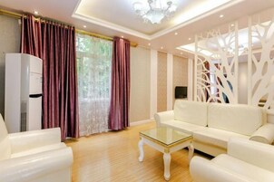 Una sala de estar con un sofá blanco, una mesa de centro de vidrio y un radiador blanco.