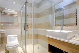 Un baño moderno con ducha de vidrio, lavamanos blanco y espejo sobre él.