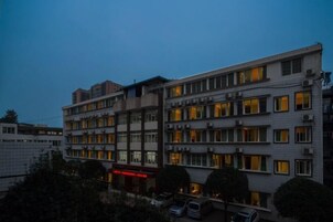 Un hotel de varios pisos con un diseño arquitectónico moderno, que cuenta con una serie de balcones y un patio central.