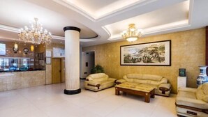 A lobby with a reception desk, two sofas, a coffee table, and a large painting on the wall. - Gongbaofu Hotel (Chongzhou)