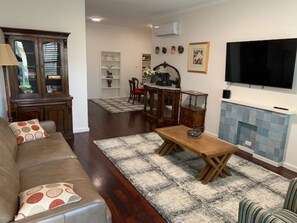 A living room with a sofa, a coffee table, a fireplace, and a television.