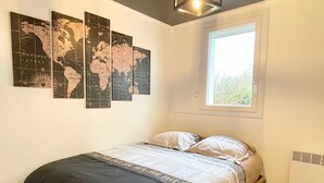 Une chambre avec un lit en bois, une carte du monde accrochée au mur, une fenêtre et un radiateur.