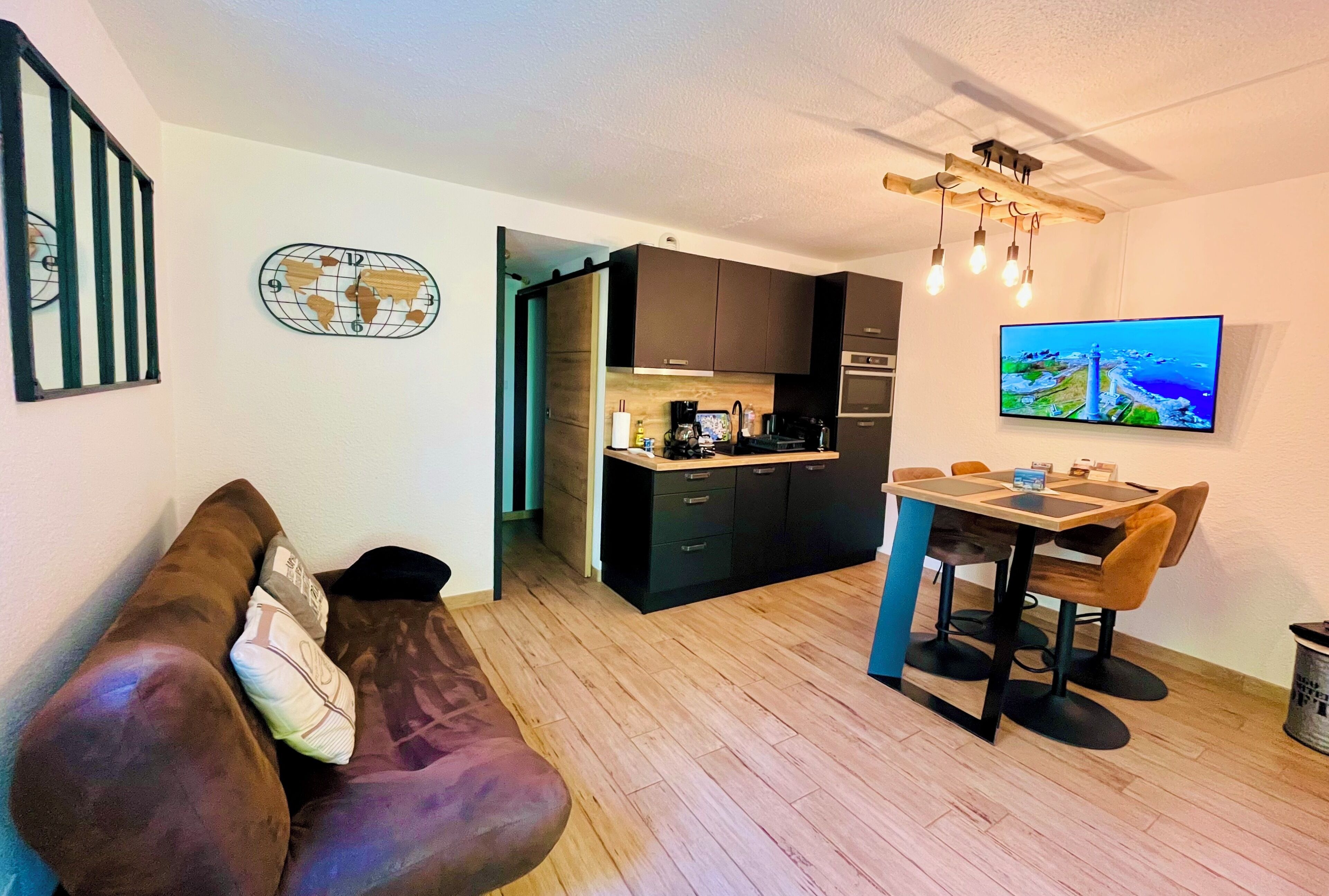 A compact living space with a kitchenette, a dining area, and a sofa.