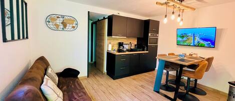 A compact living space with a kitchenette, a dining area, and a sofa.