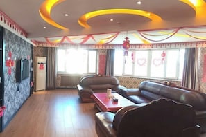 Ein geräumiges Wohnzimmer mit einer Sofagarnitur, einem Couchtisch und einem an der Wand befestigten Fernseher.