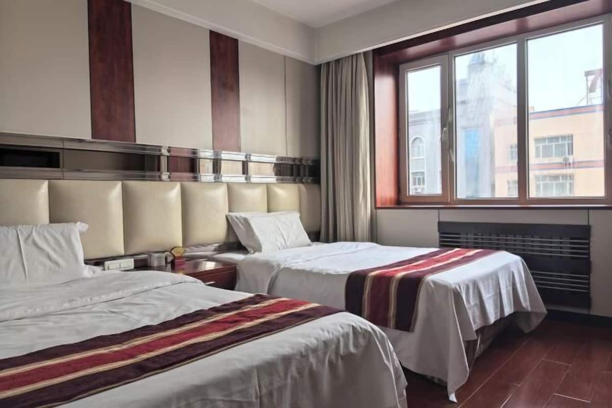 A hotel room with two beds, a large window, and a view of the city.