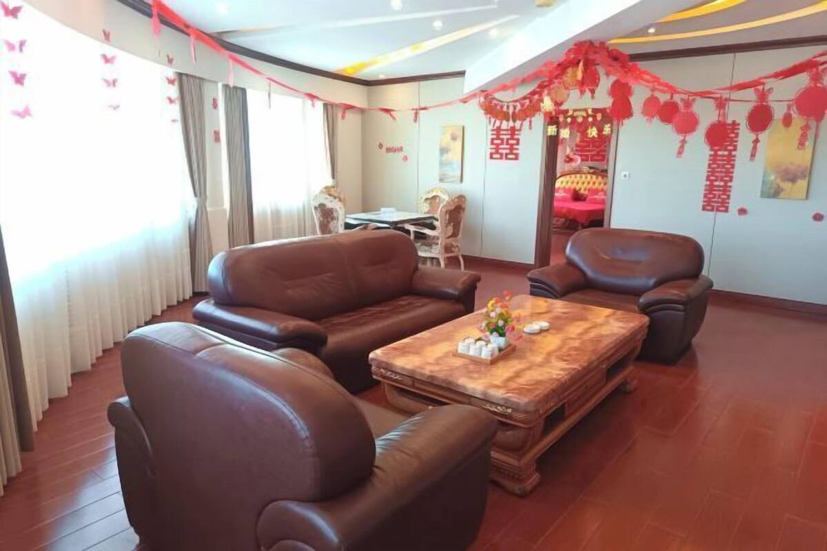 A room with leather sofas, a wooden coffee table, and red decorations.