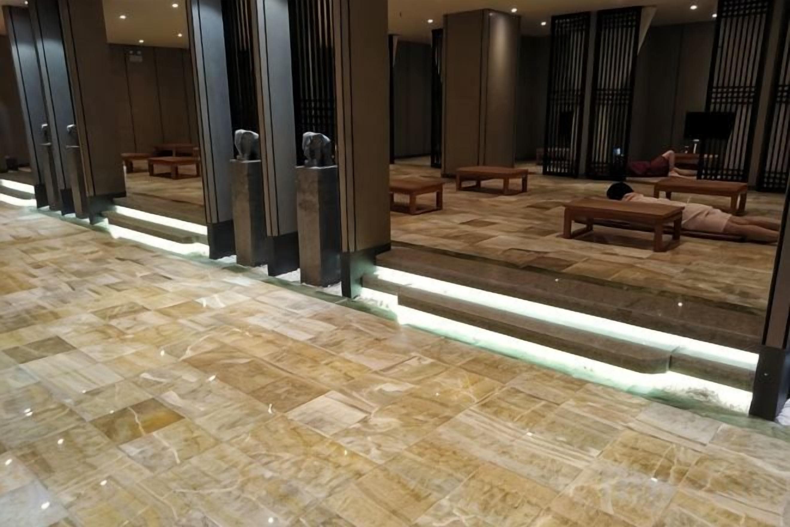 Una hall con pavimento in marmo, panche in legno e una scala.