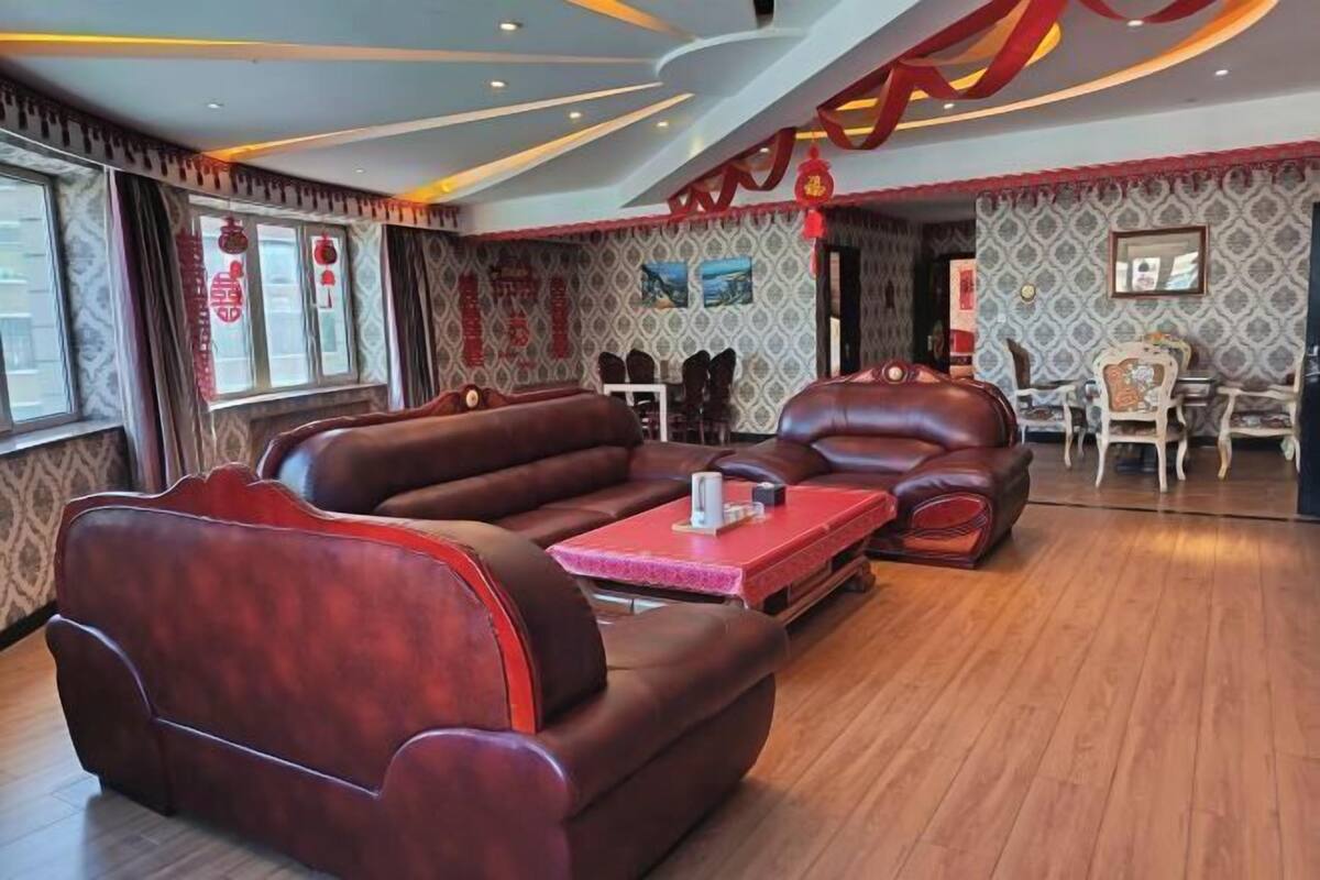 A modern living room with leather sofas, a red coffee table, and a patterned wallpaper.