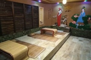 A spa area with a wooden bench, a massage table, and a wall with a mural. - Yanglin Hotel (Jixian)