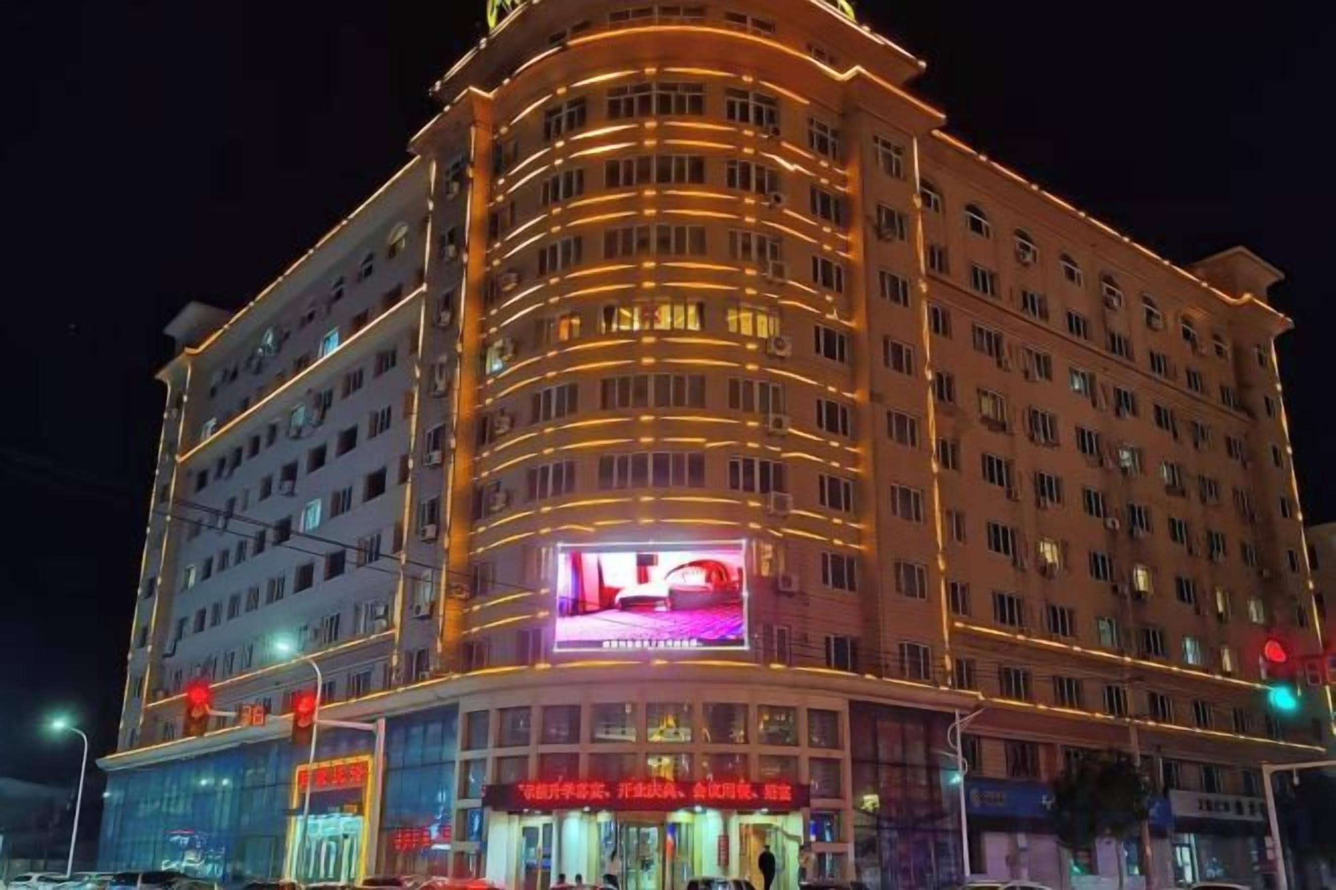 Un hotel de varios pisos con fachada curva, señalización iluminada y una entrada destacada.