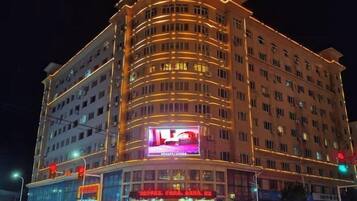 Un hotel de varios pisos con fachada curva, señalización iluminada y una entrada destacada.