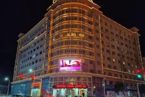 A multi-story hotel with a curved facade, illuminated signage, and a prominent entrance. - Yanglin Hotel (Jixian)