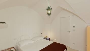 Una camera da letto con un letto, un comodino, una lampada e una porta.