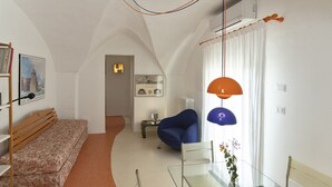 A modern living room with a sofa, a glass table, a blue chair, and a hanging lamp. - Laurel - Designer apartment in historic building 5 min from Lecce (San Cesario di Lecce)