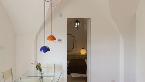 A modern room with a glass table, metal chairs, a bed with a black cover, and a hallway leading to another room. - Laurel - Designer apartment in historic building 5 min from Lecce (San Cesario di Lecce)