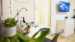 Eine moderne Küche mit Esstisch, Stühlen, einem Blumentopf und einem an der Wand befestigten Fernseher.