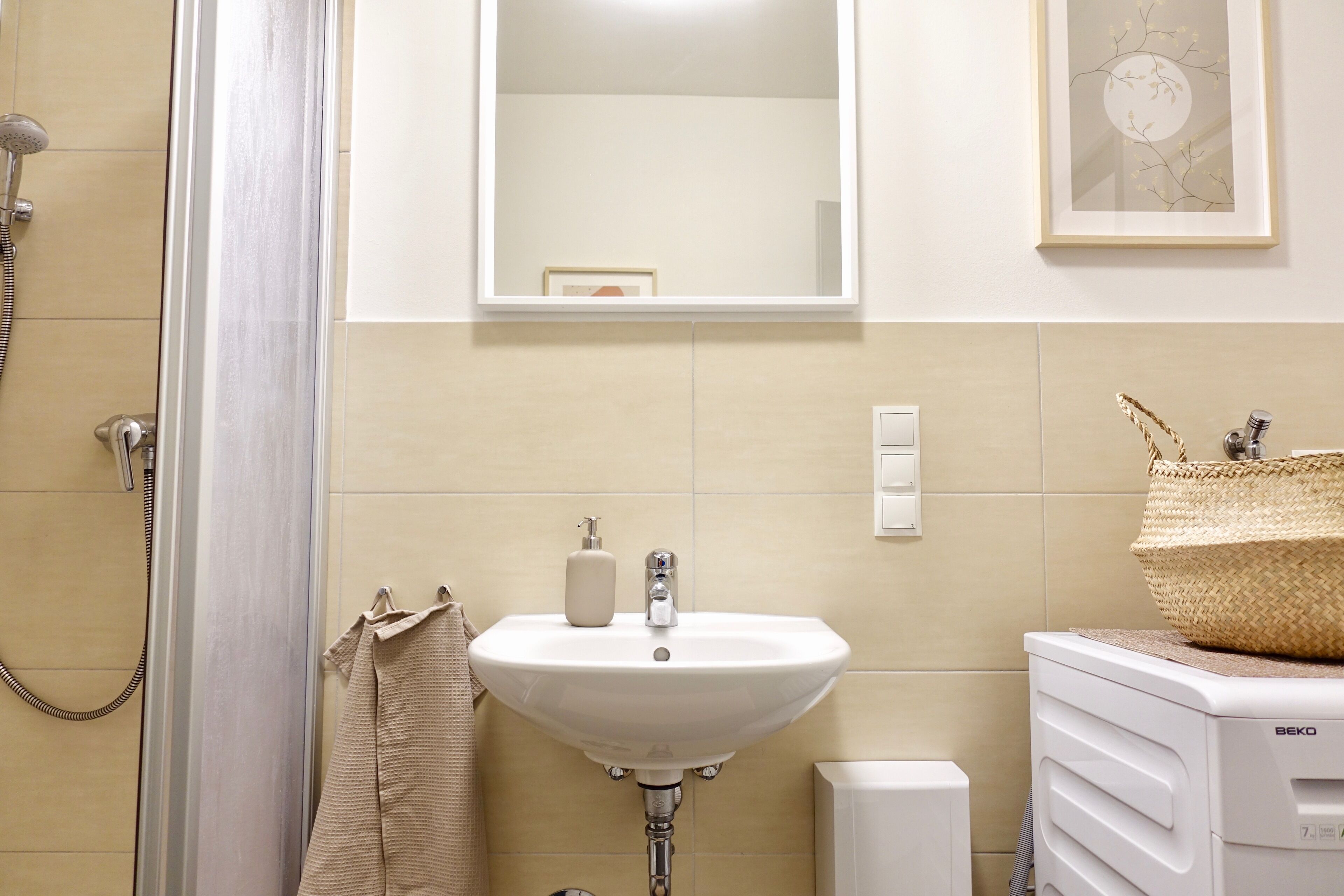 A bathroom with a shower, sink, and a towel rack.
