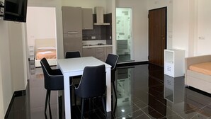 A modern hotel room with a dining area, kitchenette, and a separate living space.