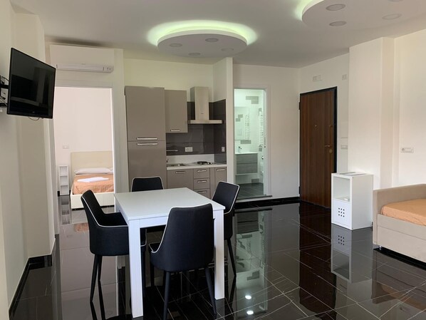 Une chambre d’hôtel moderne dotée d’un coin repas, d’une kitchenette et d’un espace de vie séparé.
