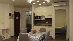 A compact hotel room with a dining area, kitchenette, and a bed.