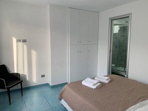 Une chambre à coucher comprenant un lit, une chaise, une armoire et un espace douche.