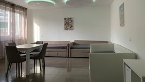 A modern dining area with a white table, two chairs, a bench, and a small white cabinet.