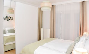 Quarto moderno com cama, cortinas e luminária pendente.