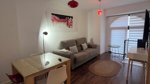 A modern living room with a dining area, a sofa, a coffee table, and a TV.