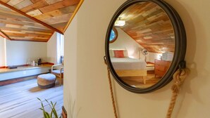 A bedroom with a wooden ceiling, a round mirror, a bed, a bedside table, and a window. - Unique Cabin w/ Riverside View + Hot Tub + Apple Pie (Ellijay)