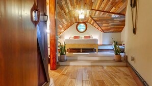 A bedroom with a wooden ceiling, a bed, and two potted plants. - Unique Cabin w/ Riverside View + Hot Tub + Apple Pie (Ellijay)