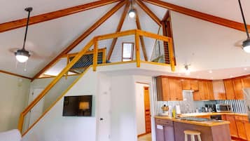 Une cuisine spacieuse dotée de meubles en bois, d’un îlot central et d’un escalier menant à l’étage supérieur.