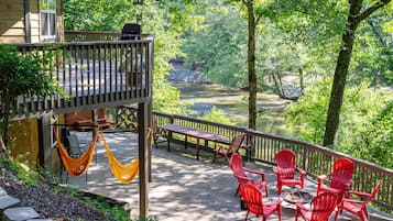 Une terrasse dotée de mobilier d’extérieur, d’un hamac et offrant une vue sur une rivière bordée d’arbres.