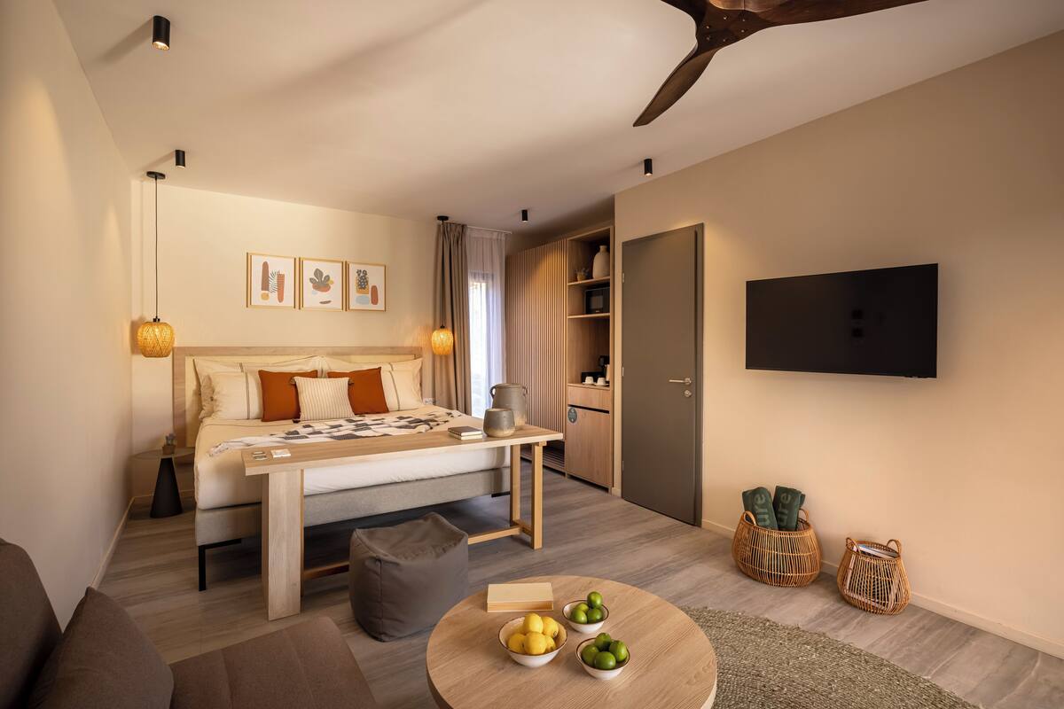 Een moderne slaapkamer met een bed, nachtkastje en een klein rond tafeltje met fruit.