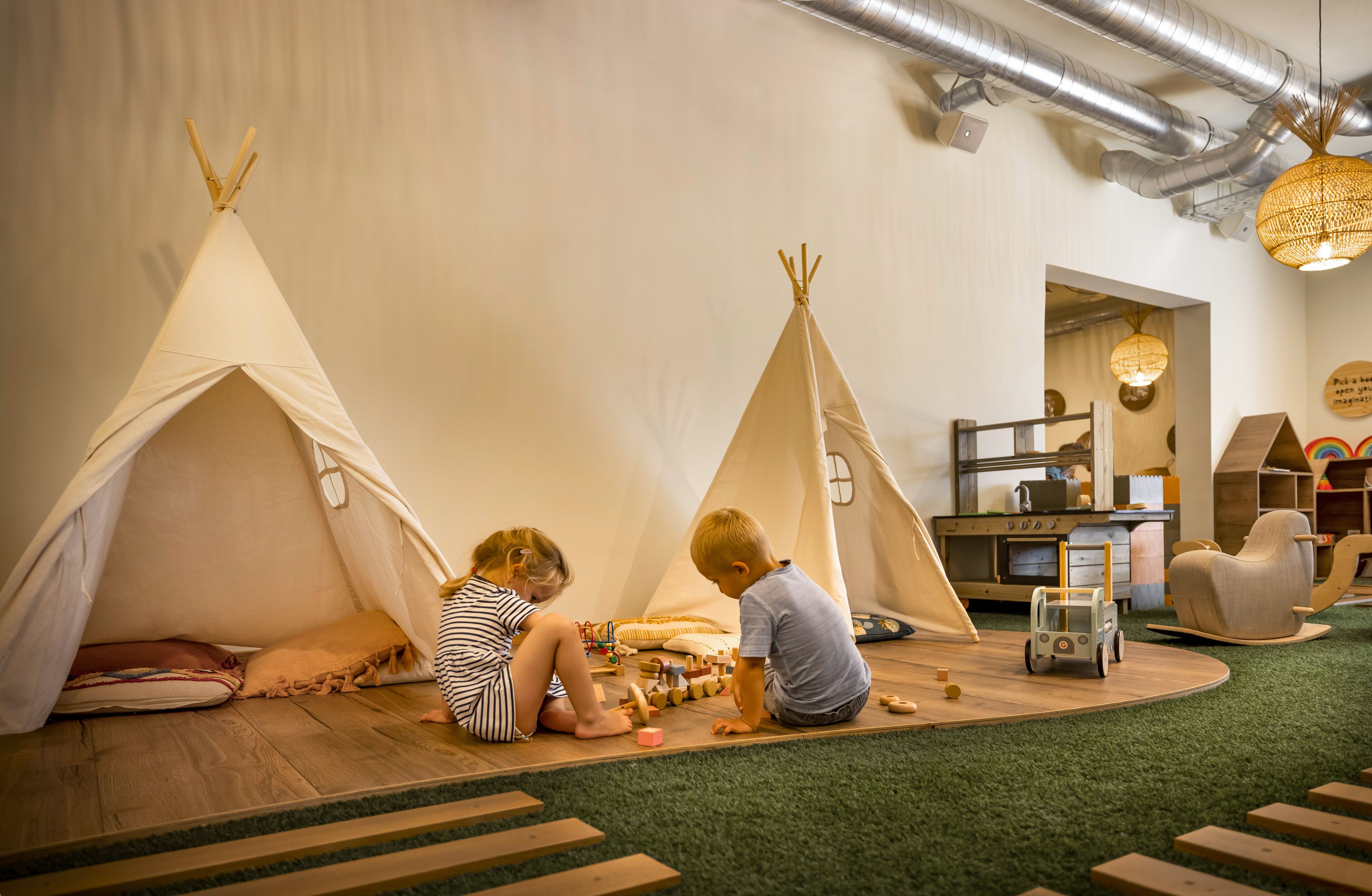 Un espace de jeux avec deux tipis, des tapis de jeu en bois et un camion jouet.