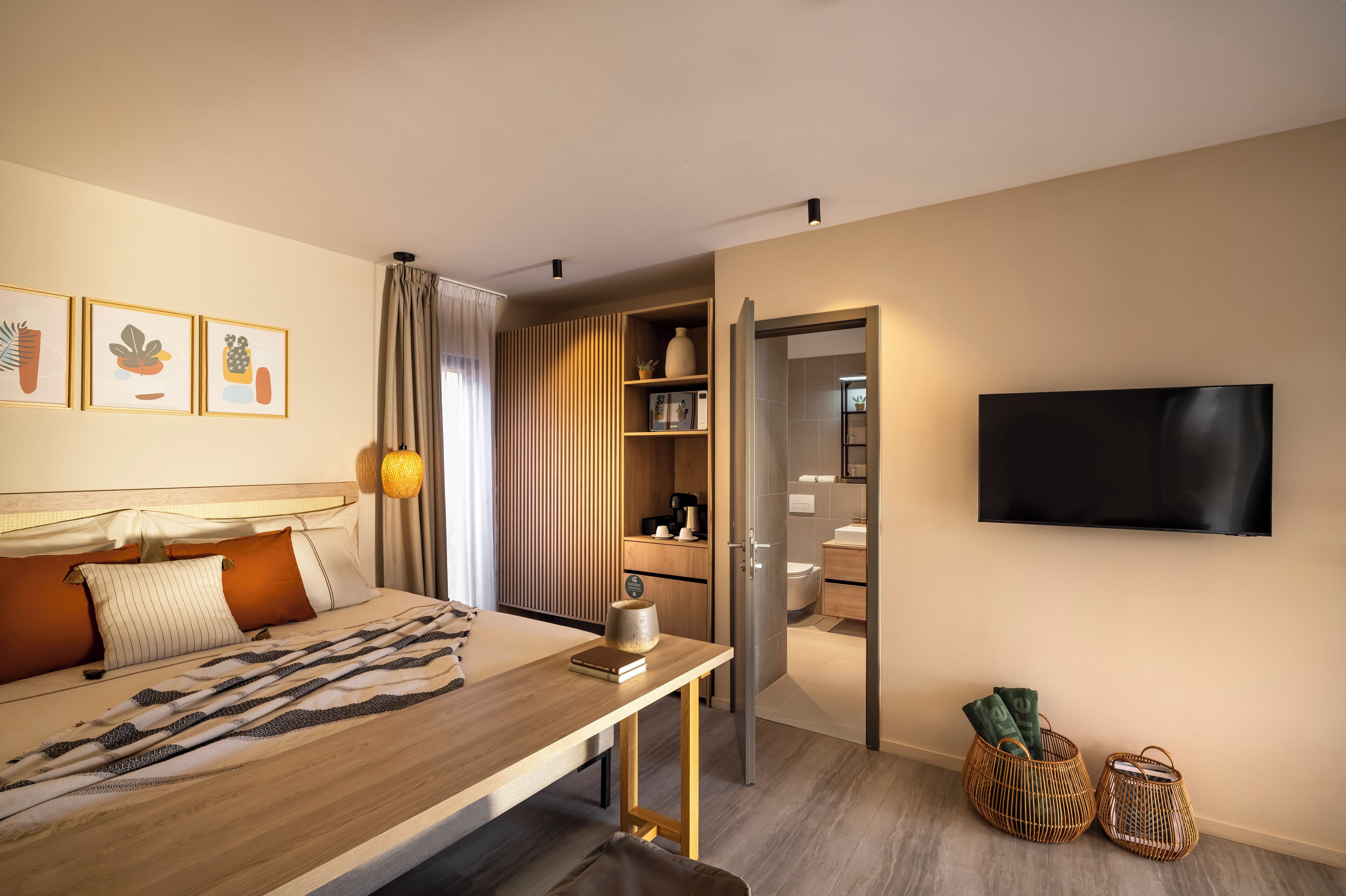 A modern hotel room with a bed, bedside table, and a TV mounted on the wall.