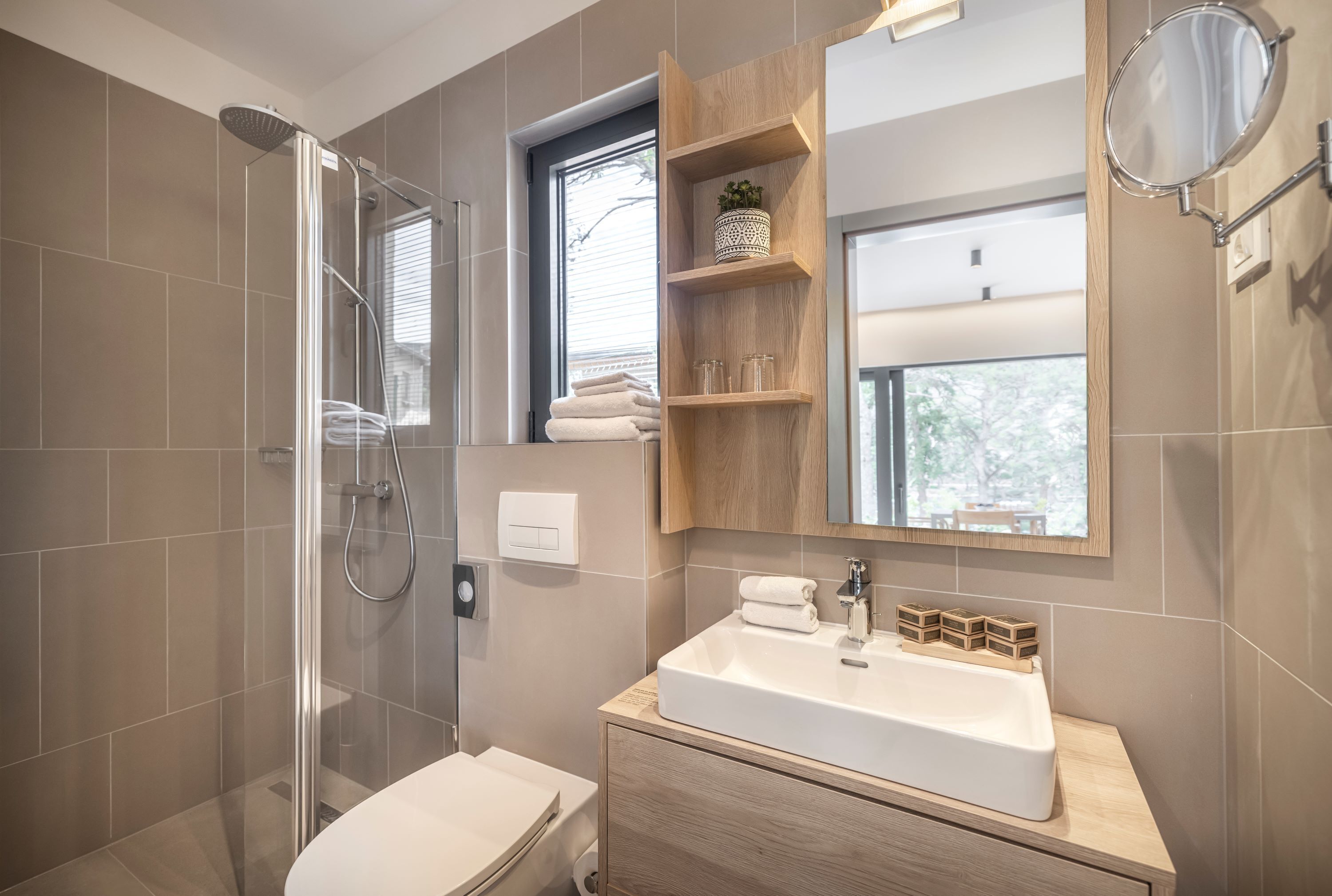 Une salle de bain moderne avec une douche à parois de verre, un meuble-lavabo en bois et une fenêtre au-dessus du miroir.