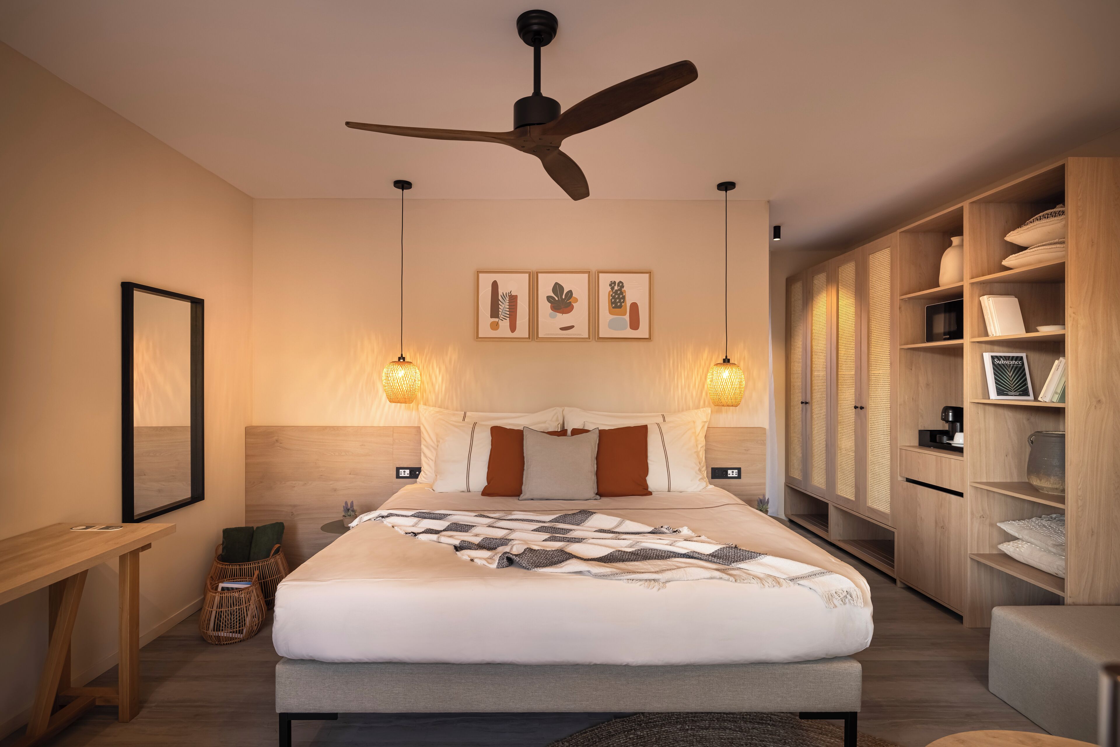 Une chambre à coucher moderne, comprenant un lit, des tables de chevet, un ventilateur de plafond, des lampes fixées au mur et une armoire en bois.