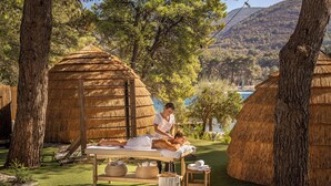 A spa area with a massage table, a small wooden stool, and a thatched-roof structure.