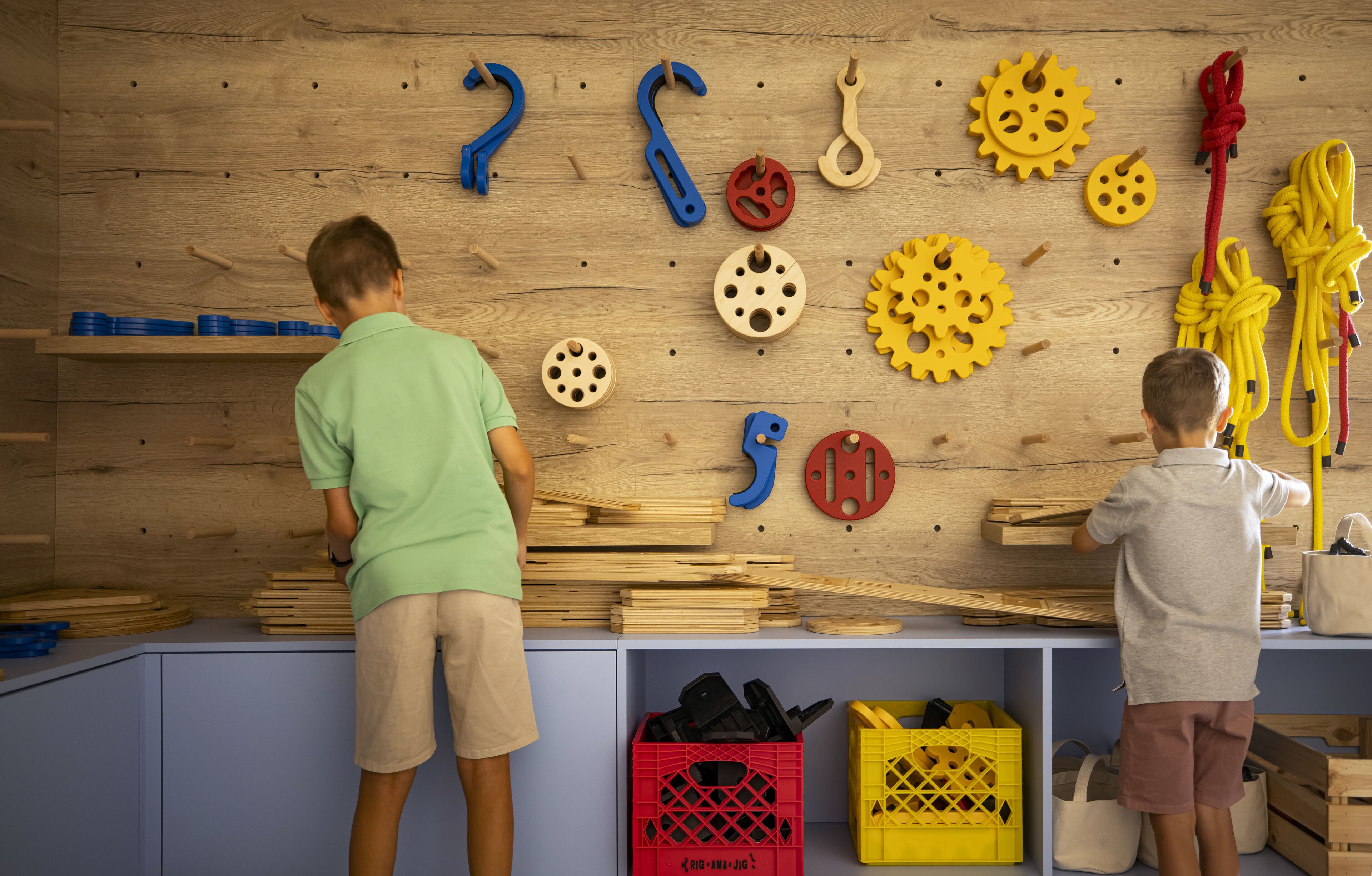Two children playing with wooden toys and tools on a shelf.