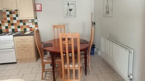 Une cuisine de taille réduite comprenant une table à manger, des chaises, une cuisinière et un radiateur.