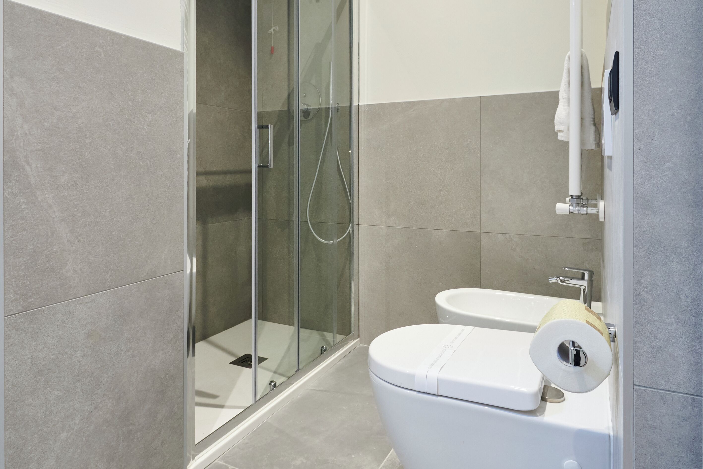 Une salle de bain moderne avec une douche à parois de verre, des toilettes blanches et un lavabo.