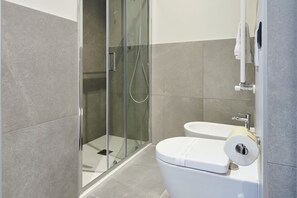 A modern bathroom with a glass-enclosed shower, a white toilet, and a sink. - STAR RIBBON (Milan)