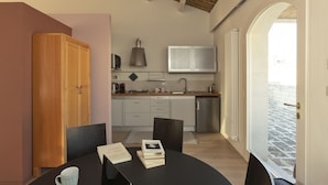 Una cucina moderna con mobili bianchi, un piano cottura integrato e una finestra con vista su una strada acciottolata.