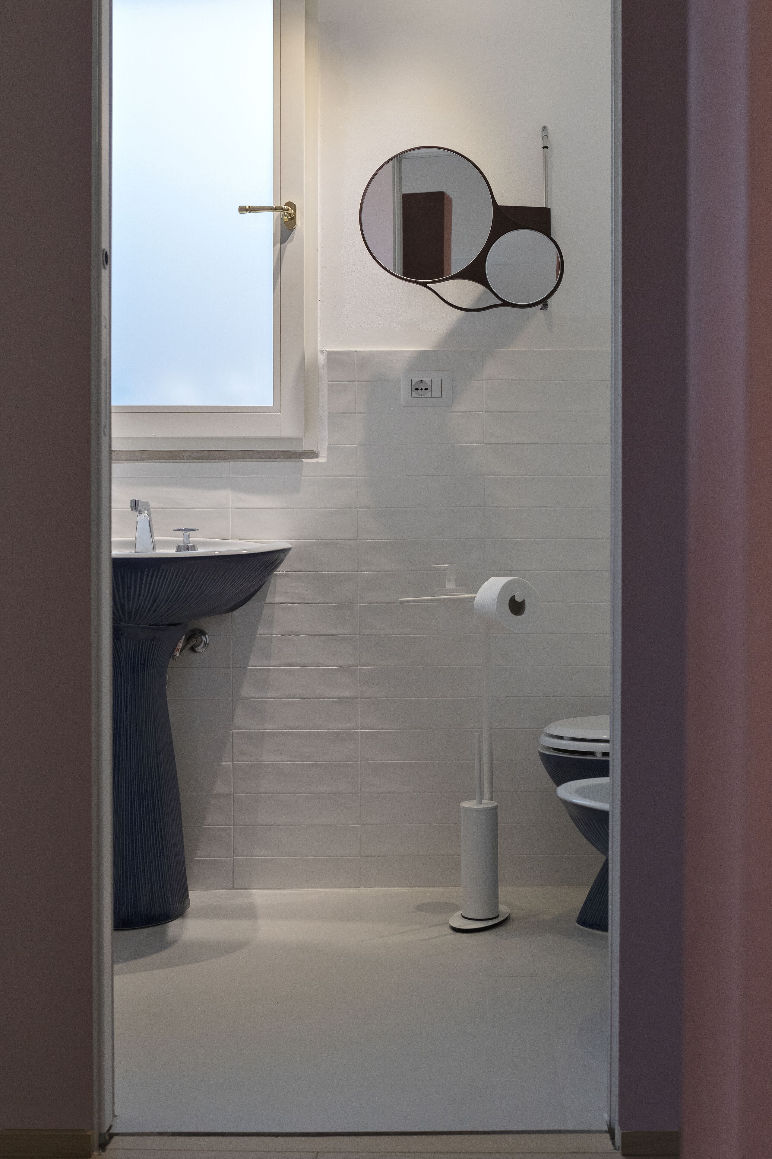 A modern bathroom with a white sink, a toilet, and a mirror.