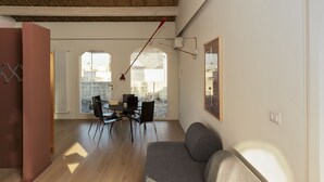 Un soggiorno moderno con divano, tavolo da pranzo e sedie. Un'ampia finestra offre luce naturale e vista all'esterno.