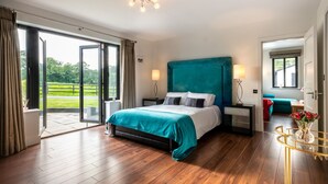 A spacious bedroom with a large bed, a view of the outdoors, and a balcony.
