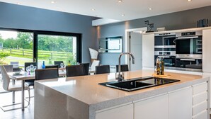 A modern kitchen with a large island, built-in appliances, and a view of the outdoors.