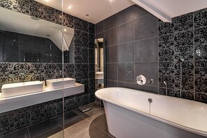 A modern bathroom with a freestanding bathtub, a vanity with two sinks, and a large mirror. - Luxury Country House on the Hill (Kenmare)